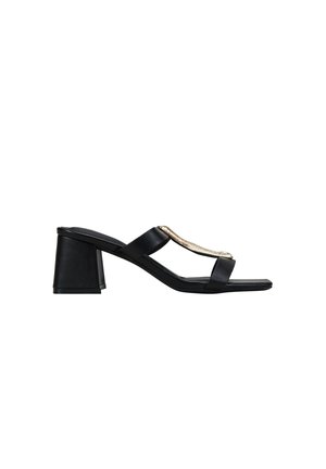 Sandalia mule negra de punta abierta con tacón bloque y dos tiras, una de ellas con un adorno metálico dorado sobre fondo blanco.