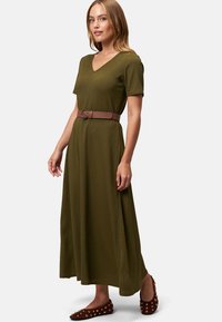 Robe maxi vert olive à manches courtes et décolleté en V, cintrée à la taille par une ceinture marron. Texture subtile, ourlet à la cheville.