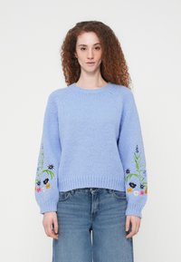 Pull en maille bleu clair avec un col rond côtelé et des manches longues, orné d'une broderie florale colorée sur les manches. Texture douce.