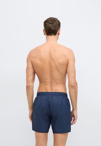 Tamsiai mėlyni plaukimo šortai iš lengvos medžiagos, su elastinga juosmens juosta ir paprastu, nesaldintu dizainu.