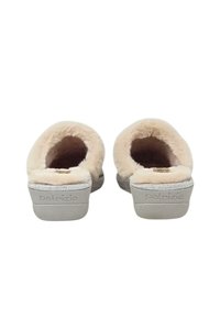 Pantofole beige con una fodera soffice simile a pelliccia e suola in gomma texturizzata. Decorate con un logo argentato sul tallone e una forma morbida e arrotondata.
