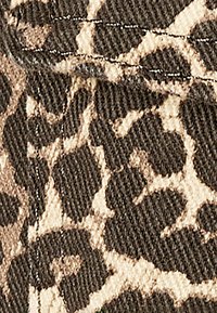 Leopardprint stof med en blanding af mørkebrune og beige farver, tekstureret overflade med synlige sømme og mønsterdetaljer.