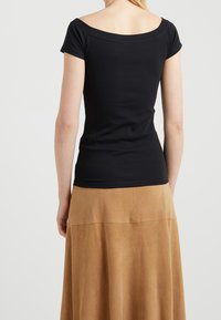 Svart axelbandslös topp i mjukt, stretchigt tyg, åtsittande i midjan med korta ärmar och en slät, sömlös design.