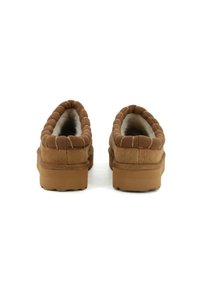 Stringate in suede marrone con interno morbido, bordi trapuntati e suola in gomma spessa. Vista posteriore che mette in evidenza la texture morbida e le caratteristiche del design.