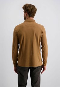 Lange mouw, bruine polo met zachte stof, met een platte kraag en een rechte zoom. Gemaakt met donkergrijze broeken.