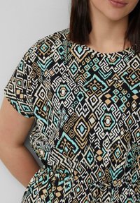 Kurzes Kleid mit geometrischem Muster in Schwarz, Türkis, Beige und Weiß. Weicher Stoff mit lockerer Passform und gerafftem Taillendesign.