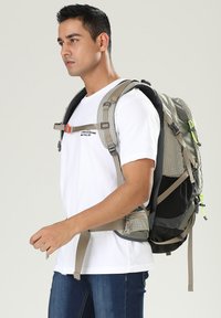 Sac à dos en tissu gris et noir, avec des bretelles rembourrées, des accents réfléchissants et une boucle ajustable. Conçu pour le confort et l'utilité.
