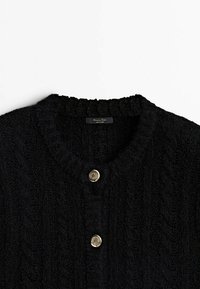 Mustan tekstuurilla neulottu cardigan, jossa on pyöreä kaula-aukko ja kaksi koristeellista hopeanväristä nappia edessä.