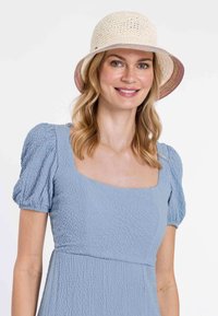 Light blue dress with textured, puffed sleeves and a square neckline; paired with a cream-colored, crocheted bucket hat featuring a colorful rim.