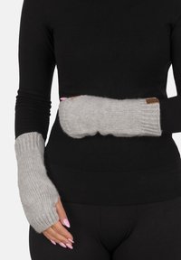 Guanti grigi senza dita realizzati in un morbido materiale a maglia testurizzato, con polsini a coste e un'etichetta in pelle marrone.
