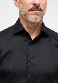 Camicia nera con bottoni, caratterizzata da una texture liscia e raffinata, colletto a punta e bottoni neri sul davanti, adatta per occasioni formali.