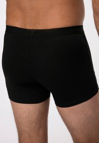 Boxer aderenti neri in cotone con una morbida cintura elastica che presenta un discreto dettaglio di branding. Texture liscia e design aderente.