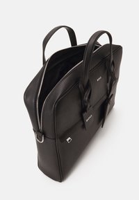 Malette en cuir noir avec deux poignées, fermeture éclair en argent, logo BOSS et étiquette amovible. Design structuré avec des textures contrastées.