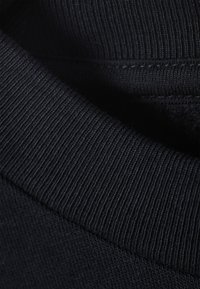 Black ribbed fabric with a smooth texture, showcasing a close-up of the collar and hem details.