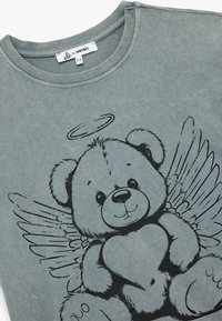 Puuvillane T-särk summutatud teal värviga, millel on graafika karust, kes hoiab südant, koos ingli tiibade ja halo’ga, ümmargune kaelus ja lühikesed varrukad.