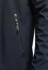 Schwarzer Jackenstoff mit glatter Textur. Verfügt über eine Reißverschlusstasche mit schwarzem Reißverschluss und einem kontrastierenden grauen Zugband am Öffnungsbereich.