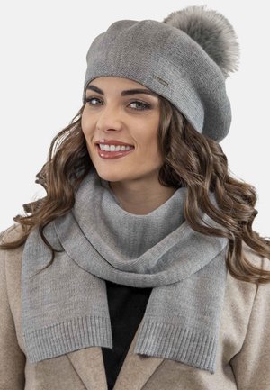 Grijze wollen baret met een faux fur pompon, gecombineerd met een bijpassende sjaal met ribbelranden en een zachte, gestructureerde afwerking.