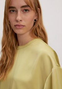 Satinbluse in blassgelb mit Rundhalsausschnitt und lässiger Passform, weichen, fließenden Ärmeln und dezenten Nähten.