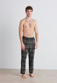 Rutig loungebyxa med svart, grön och vit mönstring, elastisk midja och avslappnad passform. Lättviktsmaterial.