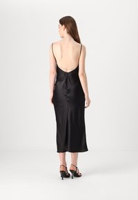 Black satin dress with spaghetti straps and a deep back neckline. Straight silhouette, mid-calf length, and discreet back zipper detail.