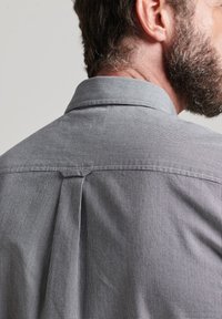 Graues kariertes Hemd von hinten, mit einer Falte am Schulterbereich, maßgeschneidertem Kragen und weicher Textur.