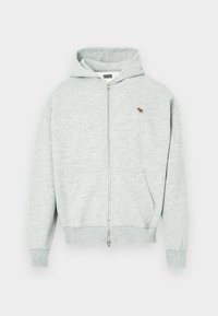 Siva zip-up kapuca, izdelana iz mehkih materialov, z zaznavnikom na sprednji strani in majhnim vezenim logotipom živali na prsih. Vključuje kapuco in žepke.