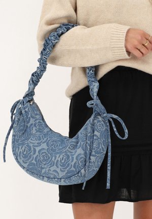 Denim schoudertas met een rozenpatroon. Voorzien van een gegatherde schouderband en trekkoordaccenten in een blauw kleurenpalet. Met ritssluiting.