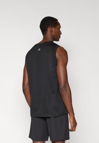 Μαύρη αμάνικη αθλητική φανέλα, κατασκευασμένη από δίχτυ ύφασμα, με στρογγυλό λαιμό και μικρό λογότυπο στο πίσω μέρος. Απλός σχεδιασμός, ελαφρύ υλικό.