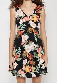 Vestido floral con escote en V, fondo negro, flores vibrantes en rosa, naranja y verde, con un cuerpo ajustado y falda acampanada.