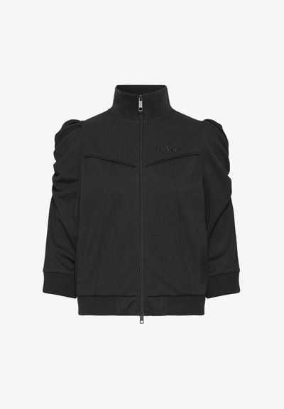 Crna bomber jakna s visokim ovratnikom, zatvaračem na patent i napuhanih rukava. Ima diskretan logo na prsima i bočne džepove.