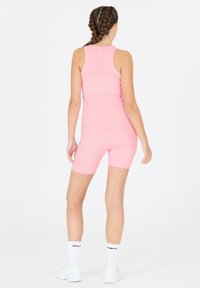 Rosa Sporttanktop und Radshorts, aus dehnbarem Material, mit gerippter Textur und schlankem Schnitt, dazu weiße Knöchelsocken und Turnschuhe.