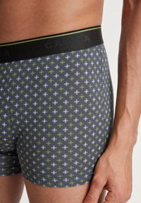 Gray boxer briefs with a subtle pattern of white and green crosses. Features a black waistband with green accents. Cotton material.