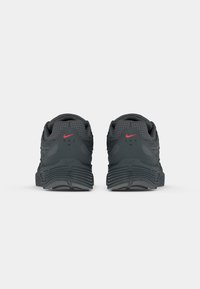 Black athletic shoes with a mesh upper, padded collar, red logo accent, and textured sole for grip, featuring a rear view perspective.