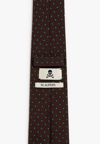 Corbata marrón con un patrón geométrico de flores verdes y amarillas. Presenta una etiqueta con un esqueleto y el texto "SCALPERS".