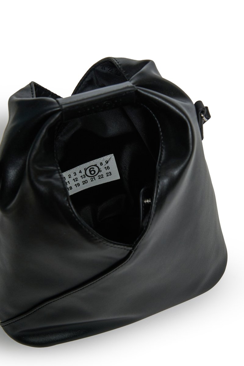 Sac en cuir noir au design doux et décontracté. Le dessus ouvert révèle un intérieur doublé de tissu et une étiquette avec des tailles numérotées.