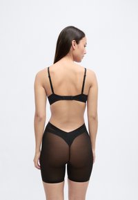 Conjunto de lingerie preta composto por um sutiã com alças ajustáveis e uma cueca de cintura alta transparente, textura suave com design minimalista.