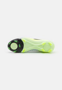 Sole di scarpa sportiva in nero e verde chiaro con motivi testurizzati e accenti arrotondati. Include un logo circolare e impugnature di un verde vivace.