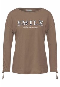 Brun långärmad skjorta i mjukt tyg med texten "SMILE" i en flerfärgad mönstrad design och "life is easy" nedanför.