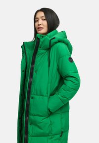 Grüne gefütterte Jacke mit Kapuze, ausgestattet mit einem Reißverschluss und Druckknopfverschluss, seitlichen Taschen und einem Logopatch an der linken Ärmel; gestepptes Design.