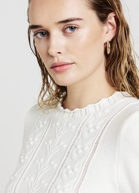 Weißer Pullover mit strukturiertem Blumenmuster, rundem Halsausschnitt und geripptem Saum. Verfügt über gestrickte Details und erhöhte Akzente überall.