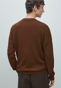 Hnědý pletený svetr s kulatým výstřihem, žebrovanými manžetami a lemem. Hladká textura, přiléhavý střih a minimalistický design pro univerzálnost.