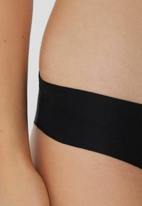 Czarny elastyczny pasek odzieżowy o gładkiej teksturze, bezszwowym wzorze i minimalistycznym kroju w pasie.