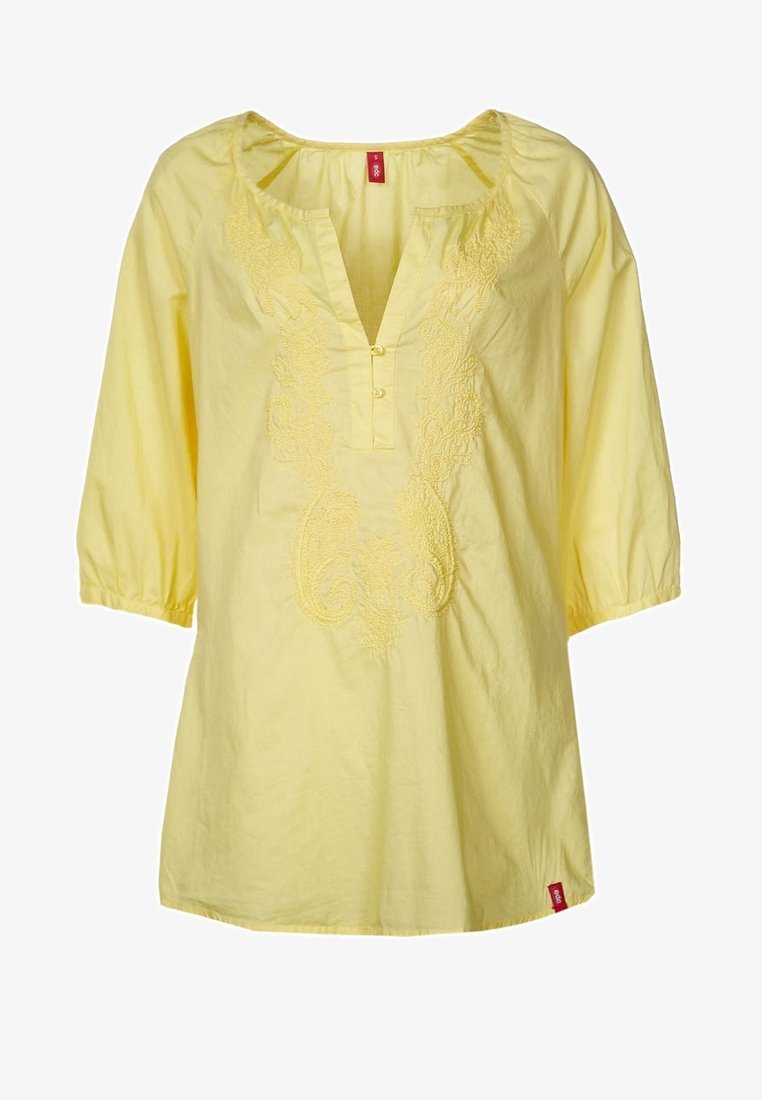 Tunique jaune à manches longues avec motifs floraux brodés sur le devant et ouverture en V avec deux boutons.
