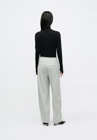 Sort langærmet top med tætsiddende design kombineret med lysegrå, vidde bukser med tekstureret mønster og elastisk linning.