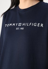 Sötétkék pamut póló kerek nyakkal, elöl fehér "TOMMY HILFIGER EST. 1985" logóval. Puha tapintás, laza szabás.