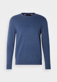 Pull bleu à manches longues et col rond avec un petit logo rouge, blanc et noir sur la poitrine gauche, avec poignets et ourlet côtelés.