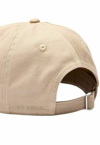 Beige keps med rund topp, tillverkad av texturerat tyg, har en broderad logotyp på baksidan och ett justerbart metallspänne.