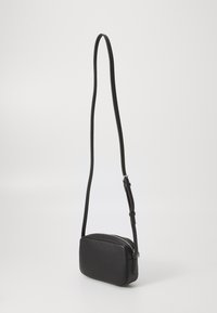 Black leather crossbody bag with a rectangular shape, textured surface, zip closure, and an adjustable shoulder strap.