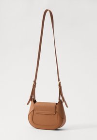 Bolsa crossbody castanha em pele com uma superfície texturizada, fecho de aba e alça ajustável; apresenta uma forma arredondada e hardware minimalista.
