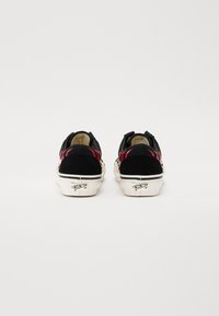 Zapatillas de skate de ante negro con acentos rojos, suela blanca y detalle del logo en el talón. Diseño estándar de corte bajo con cuello y lengua acolchados.
